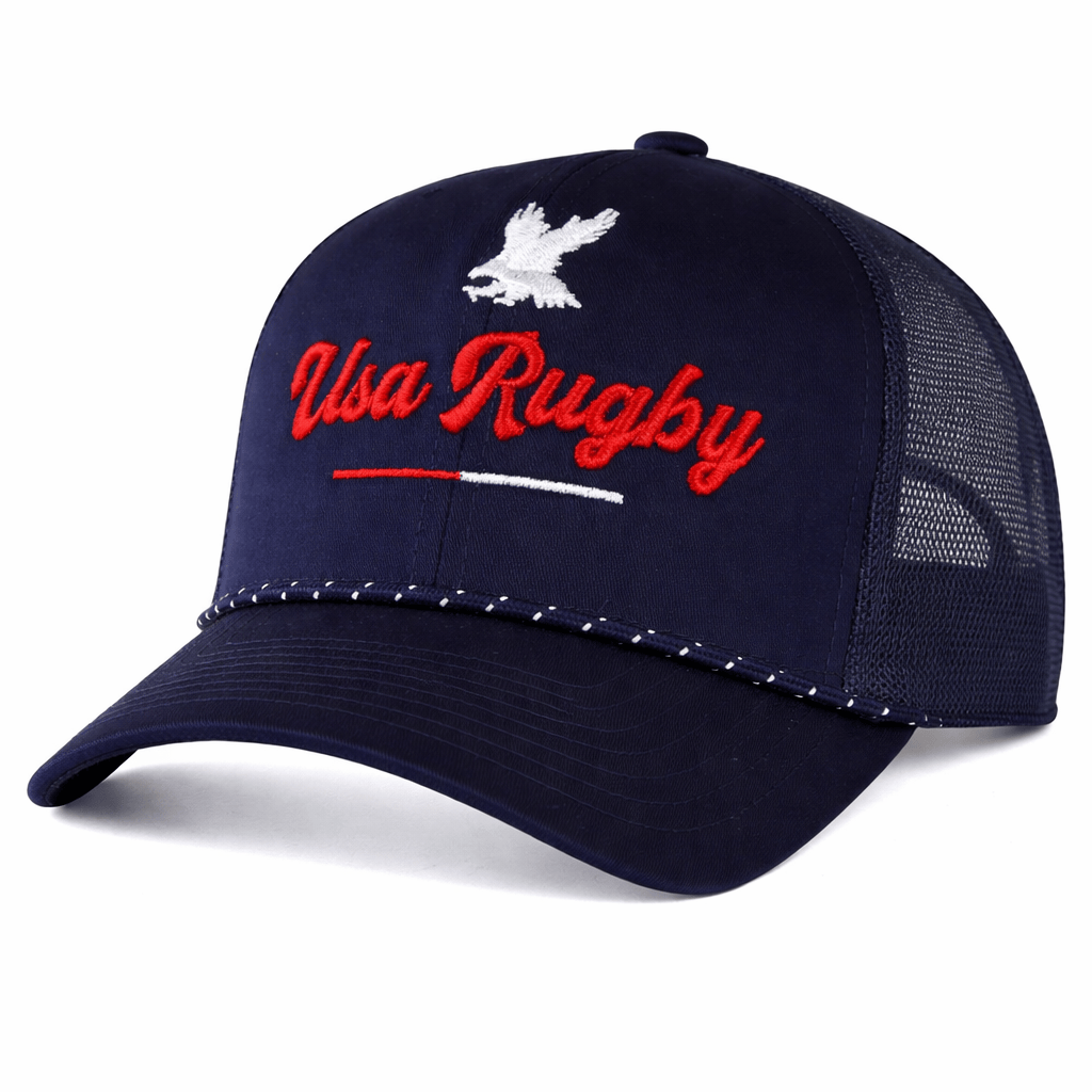 The EMB Augusta USA Rugby Elevated Eagle Braid Trucker Cap features a navy blue design with a white eagle graphic, red "USA Rugby" text, white stitching on the bill, and breathable mesh back.