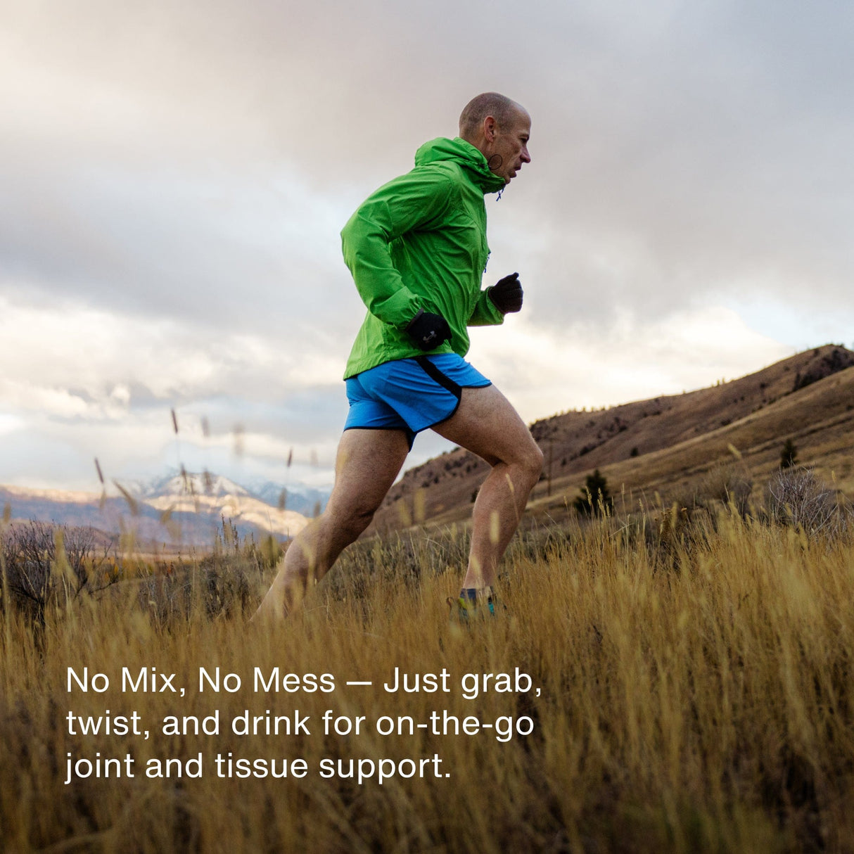 A man in a green jacket and blue shorts runs uphill through tall grass with mountains behind him; text promoting Momentous Collagen Shot 15-Packs by Momentous for joint health overlays the image.