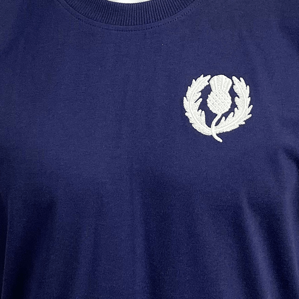 The Ellis Rugby Scotland Rugby 1990 Grand Slam Shirt is dark blue with a white embroidered thistle emblem on the upper left side, capturing the spirit of the 1990 triumph.