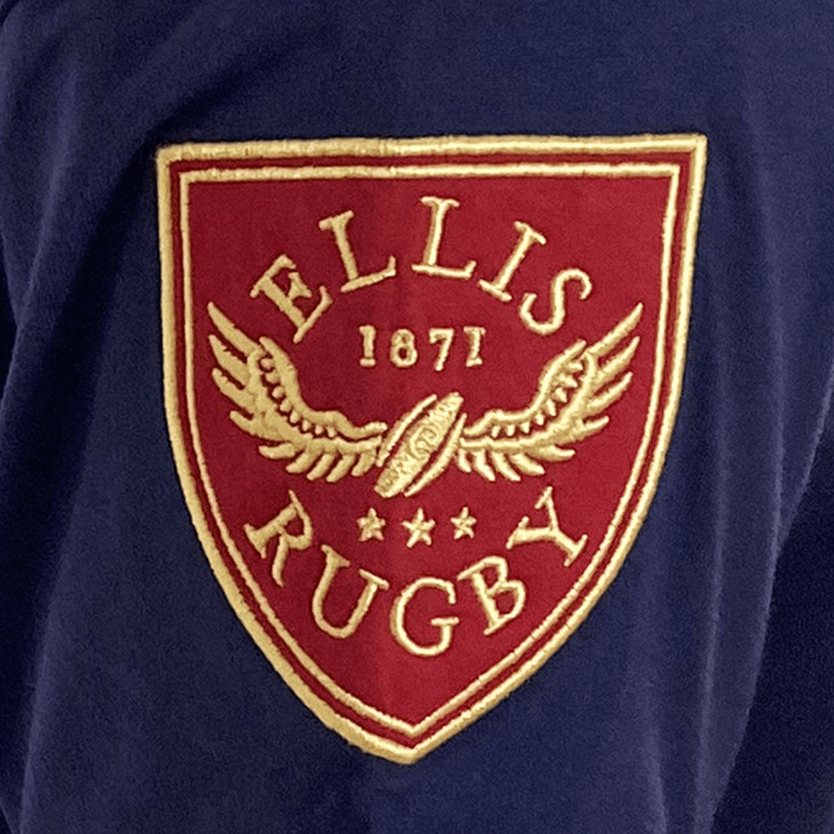 The Ellis Rugby Scotland Rugby 1990 Grand Slam Shirt is blue with a red and gold "ELLIS RUGBY 1871" crest, featuring a winged rugby ball and stars, celebrating the legacy of the Grand Slam.