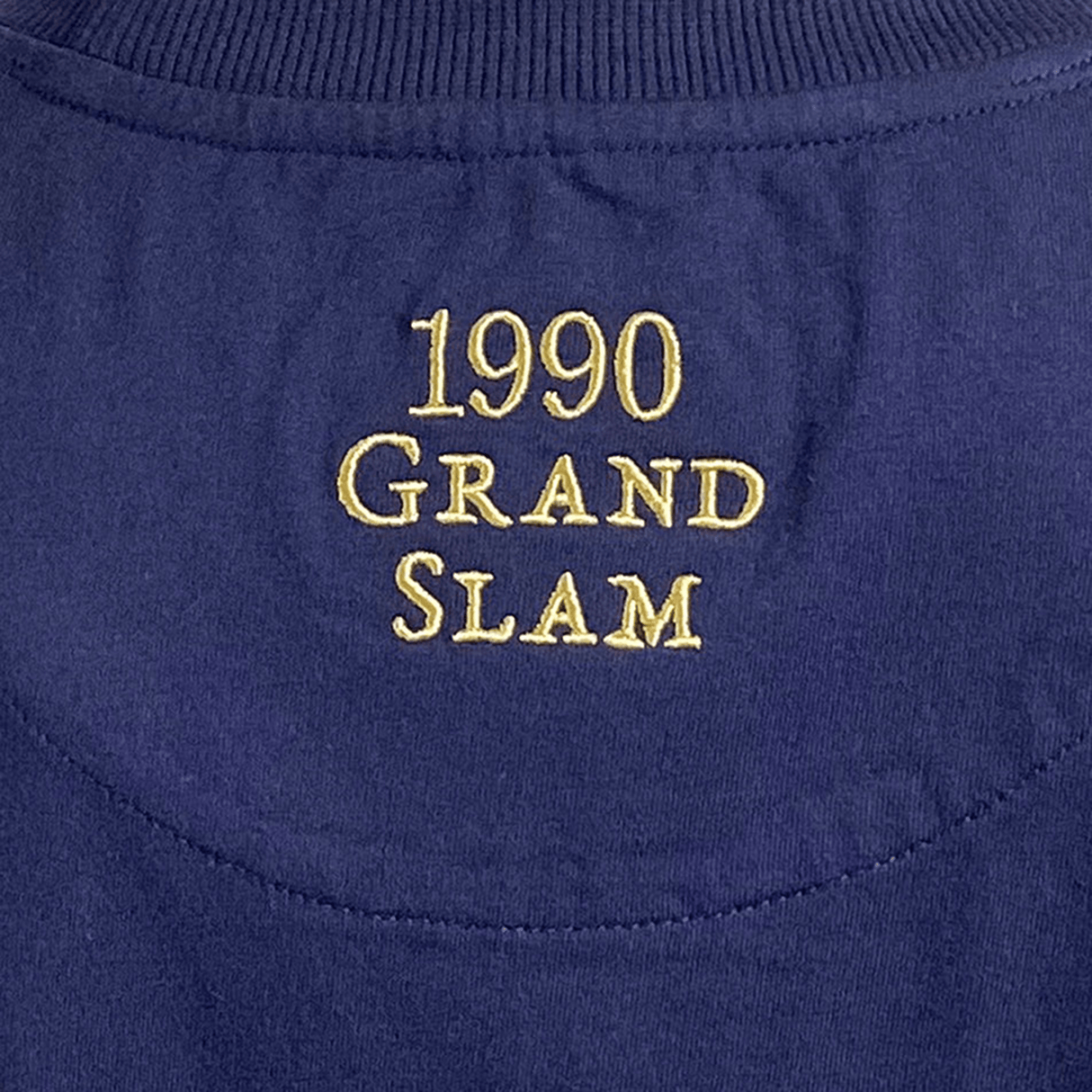 Close-up of "Scotland Rugby 1990 Grand Slam" in yellow on dark blue fabric, a tribute to Ellis Rugby's legacy.