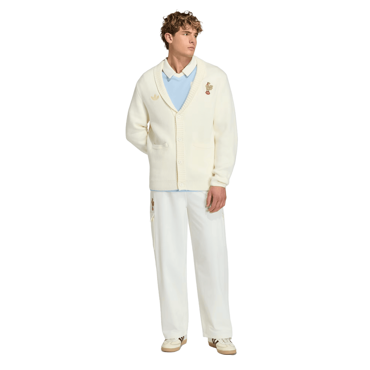 A man faces forward in the adidas France FFR 120 Year Cardigan—honoring 120 years of French rugby—styled with a light blue shirt, white pants, and beige shoes against a plain white background.