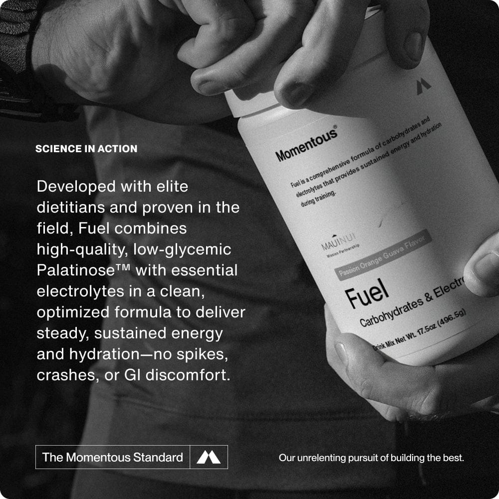 Someone holds a container of Momentous Fuel by Momentous, a carb electrolyte formula for sustained energy, with text highlighting its benefits and clean ingredients in the background.