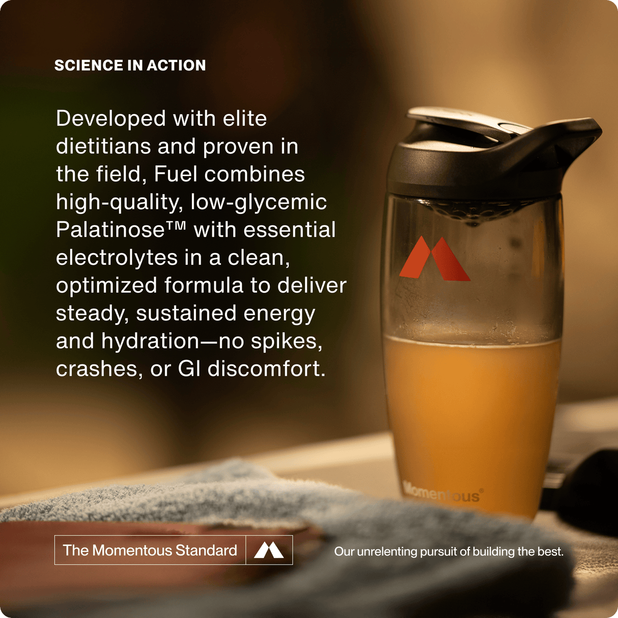 A shaker bottle with an orange drink sits on a table next to text about Momentous Fuel 10-Travel Packs, a carb electrolyte formula by Momentous designed to deliver sustained energy and hydration for endurance exercise.