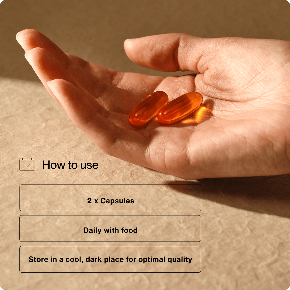 A hand holds two orange capsules; instructions say to take 2 Momentous Omega-3 capsules daily with food and store in a cool, dark place for best quality. Supports brain and heart health. Brand: Momentous.