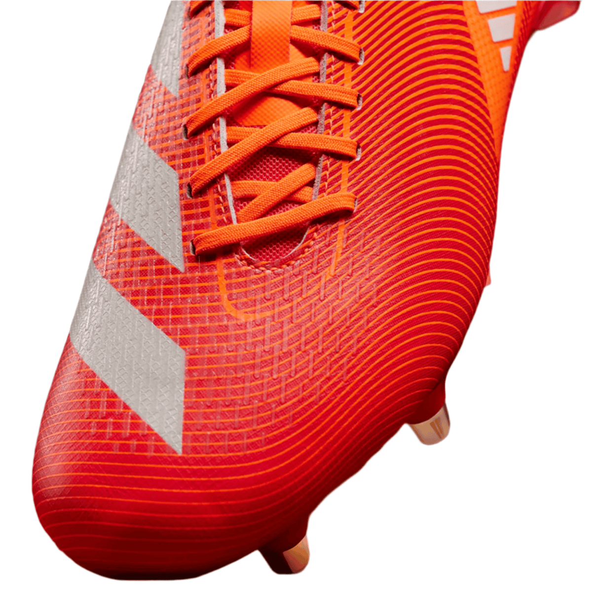Close-up of the adidas Adizero RS15 Pro SG Rugby Boot in Lucid Red, White, and Team Solar Orange, featuring white stripes, orange laces, and a textured surface designed for soft ground play—showing part of the shoe’s upper and its studs.