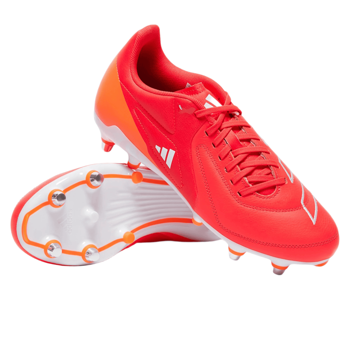 The adidas RS15 Elite SG cleats in Team Solar Orange, White, and Lucid Red feature asymmetrical laces with one shoe upright and the other showing its metal-studded sole reminiscent of rugby boots.