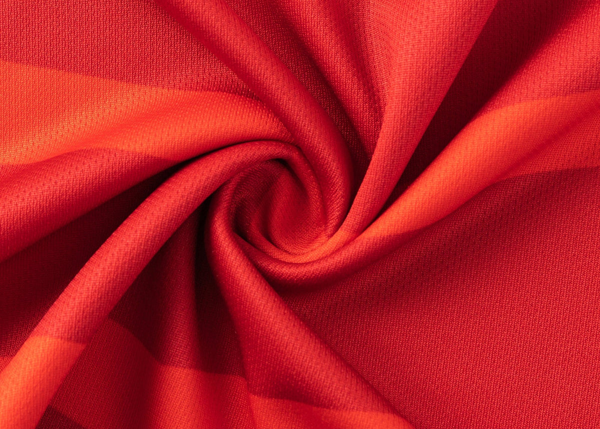 Close-up of the Dolphins NRL 25/26 Replica Home Jersey by Classic Sportswear, featuring vibrant red fabric with swirling folds, textured surface, and various shades of red reminiscent of classic sportswear design.