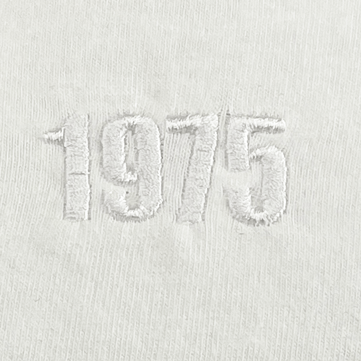 The EMB S&S Activewear USA Rugby Elevated Tonal Comfort Tee features white fabric and subtle "1975" tonal embroidery, making it a perfect pick for classic USA Rugby style fans.