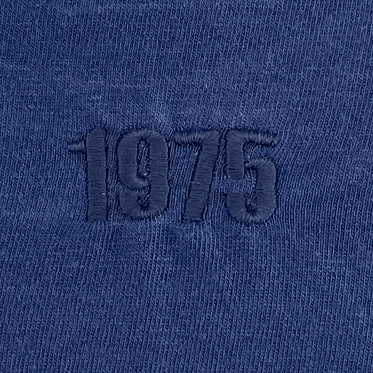 Close-up of the EMB S&S Activewear USA Rugby Elevated Tonal Comfort Tee - Navy, showing "1975" embroidered in darker blue thread on 100% ring-spun USA cotton, inspired by classic rugby style.