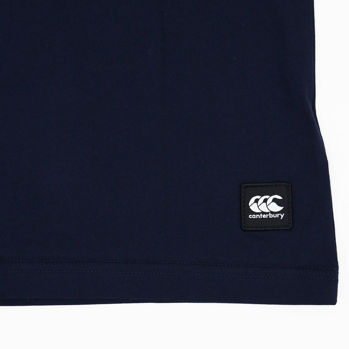 Navy blue fabric features a black rectangular Canterbury brand logo patch sewn near the bottom edge, complete with white text and logo—ideal for fans of the Canterbury Women's Uglies Logo T-Shirt or anyone looking for an authentic women's rugby t-shirt style.