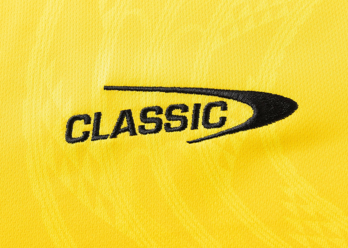 The Hurricanes Super Rugby 25/26 Replica Home Jersey by Classic Sportswear showcases elegant black "CLASSIC" embroidery and a curved design on yellow fabric, echoing the iconic style.