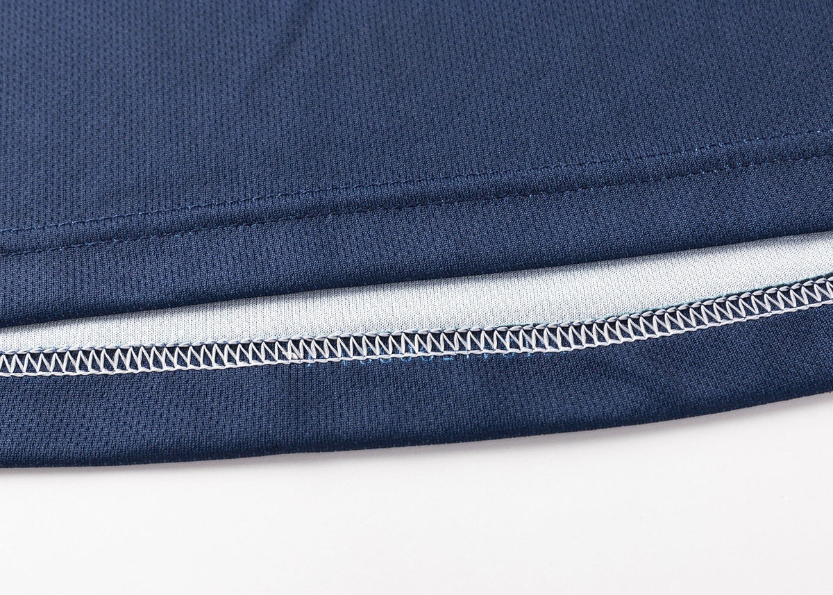 Close-up of the hem of a blue fabric resembling the Highlanders Super Rugby 25/26 Replica Home Jersey by Classic Sportswear, highlighting detailed stitching and a white inner lining with moisture-wicking technology.