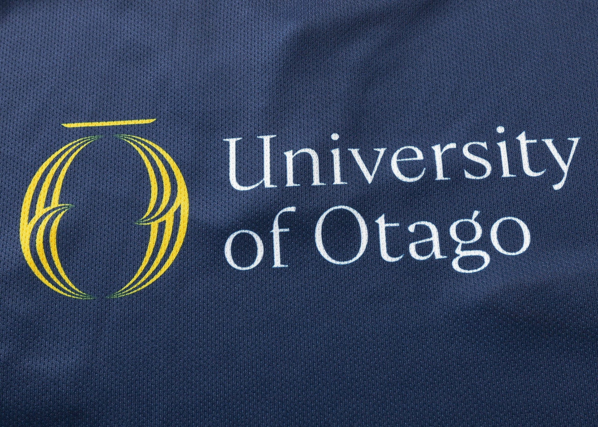 The Highlanders Super Rugby 25/26 Replica Home Jersey by Classic Sportswear features "University of Otago" text and a stylized yellow logo on a dark blue, moisture-wicking fabric.