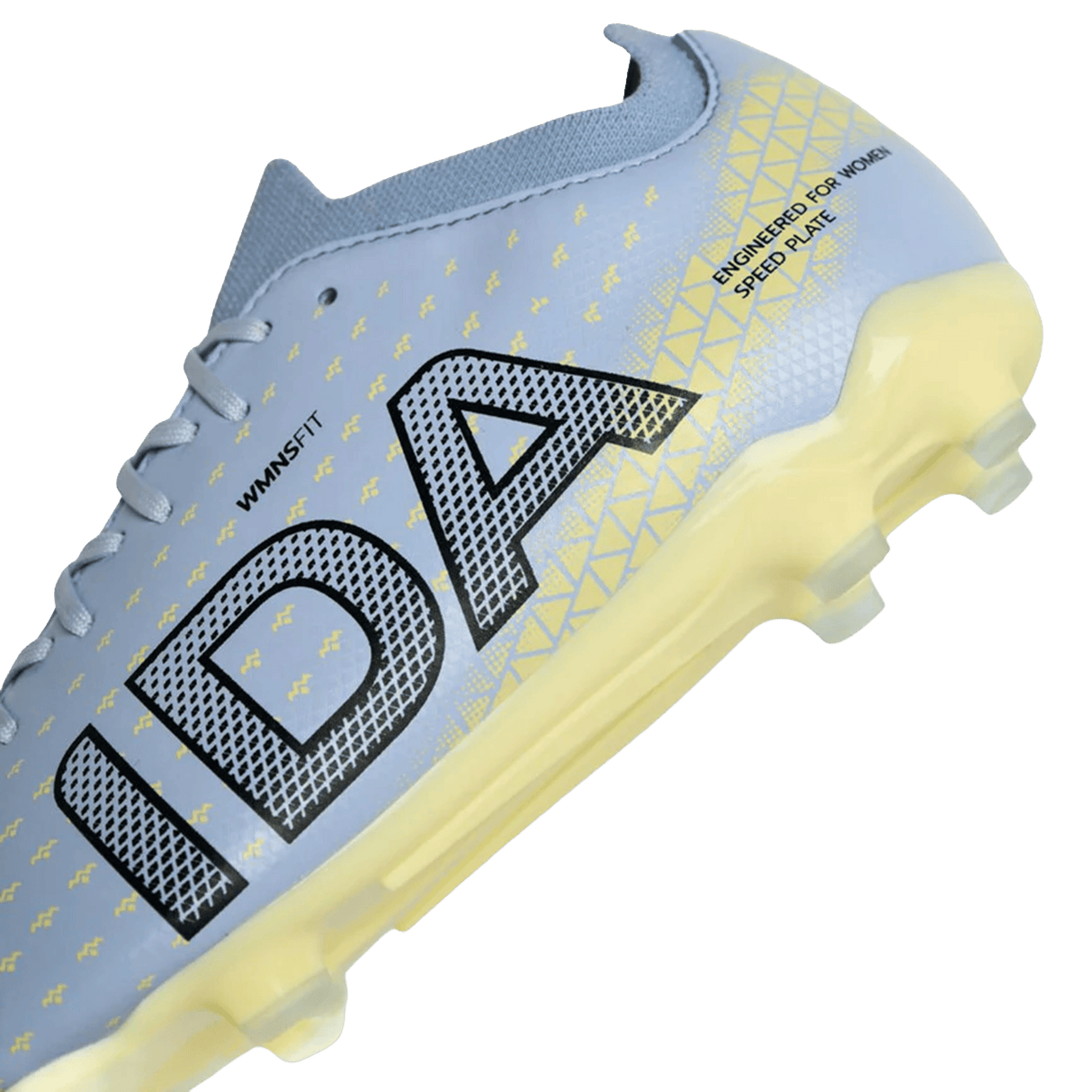 Close-up of the IDA Sports IDA Helia Club FG women's soccer cleat in light blue, showcasing yellow geometric patterns and translucent yellow sole studs, with "IDA" printed on the side.