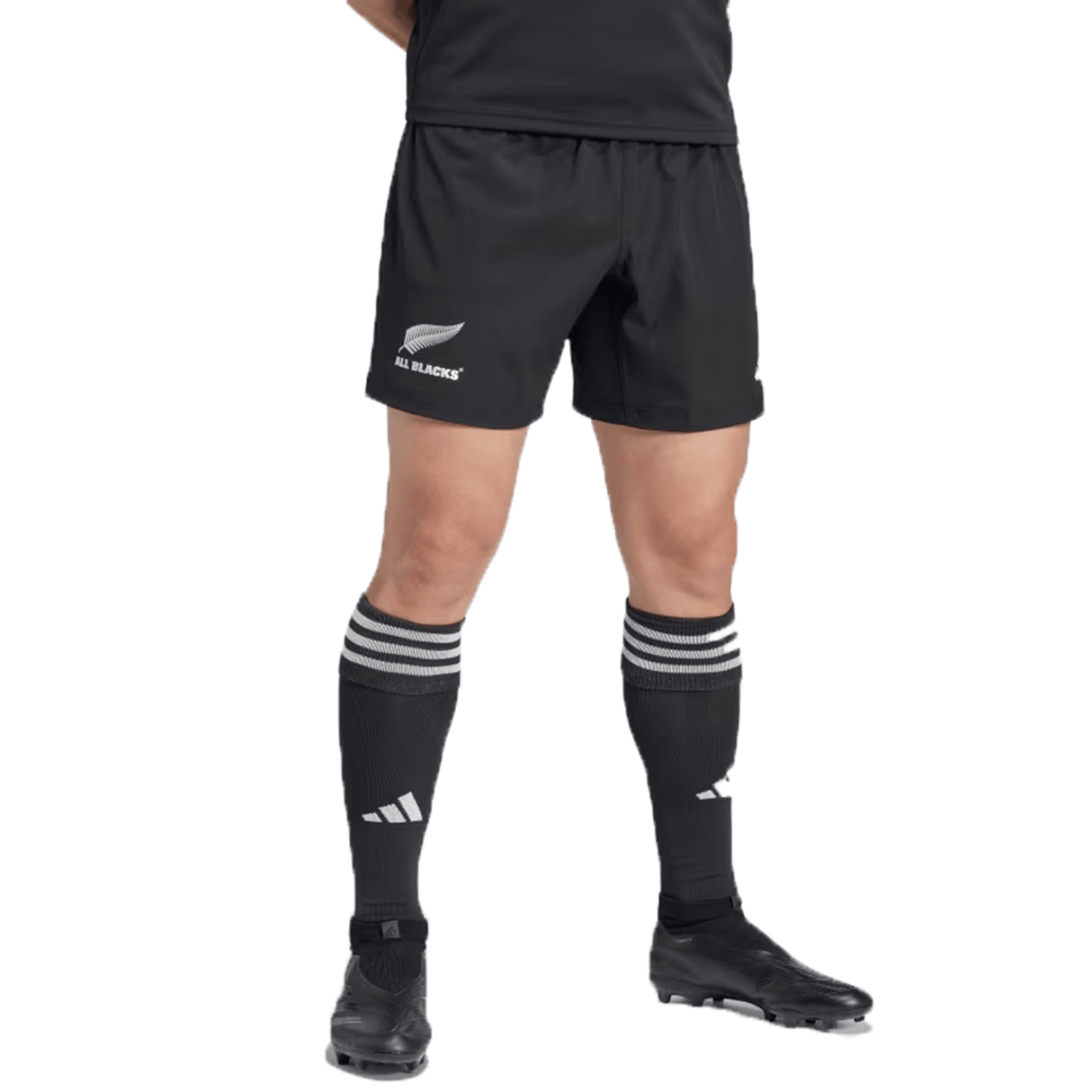 A person wearing the All Blacks 24/25 Home Shorts by adidas, crafted from recycled materials, paired with black knee-length socks featuring white stripes, and black cleats.