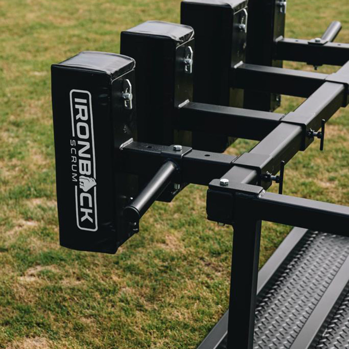 Close-up of the IronBack Gorilla 8 Man Scrum Machine, featuring black padded sections branded with "IronBack Scrum," positioned on a grassy field—providing essential scrum training equipment for dedicated rugby teams.