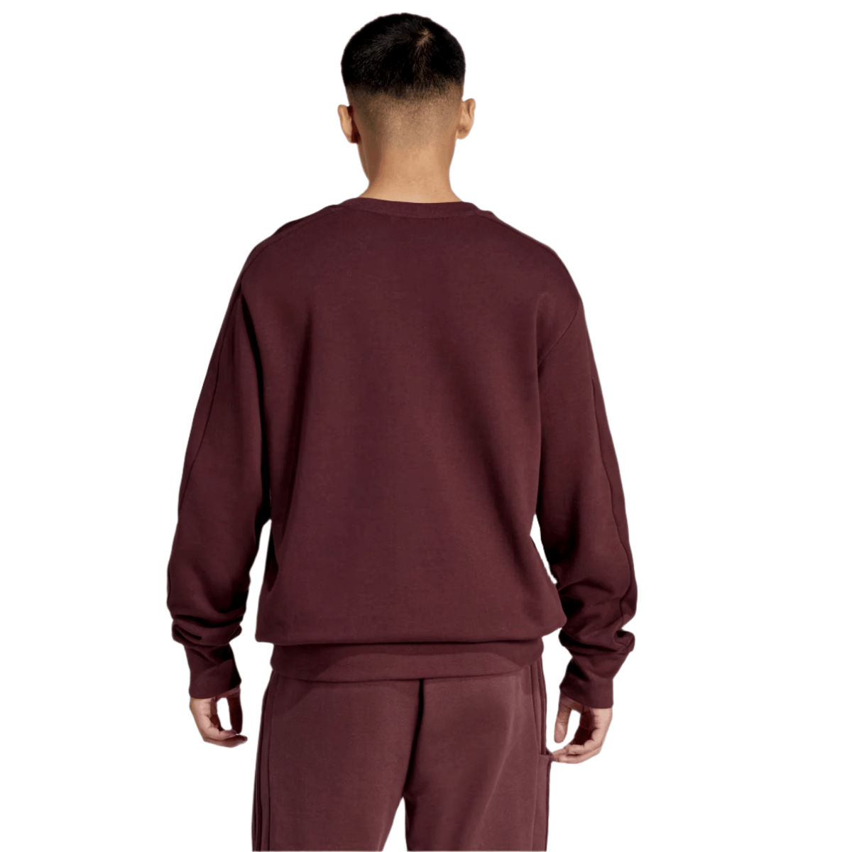 A person stands with their back turned, wearing an All Blacks 24/25 Fan Crewneck Sweatshirt by adidas in maroon and matching pants against a plain gray background.