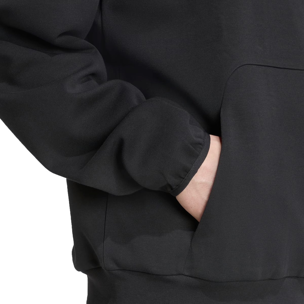 Someone wearing the All Blacks 25/26 Presentation Hoodie by adidas in black, with their right hand in the front pocket, shown from shoulders to waist.
