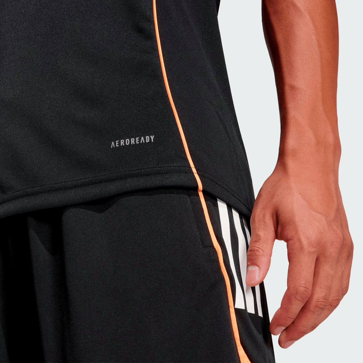 A person wears black athletic shorts and the adidas All Blacks 26/27 Marvel Performance Training Tee; only the lower torso and right hand are visible.