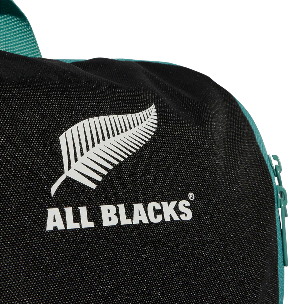 Close-up of the All Blacks 25/26 Backpack by adidas, showing the white fern logo, "ALL BLACKS®" text, and a teal zipper on the right side.