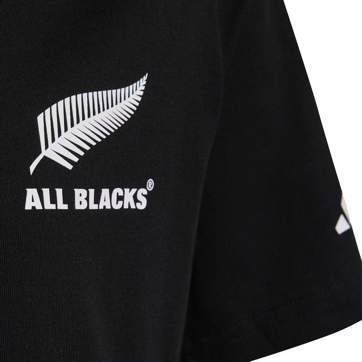 Close-up of the All Blacks 26/27 Marvel Leisure Tee by adidas, a black shirt with a white silver fern and "ALL BLACKS®" on the chest, celebrating New Zealand rugby heritage.
