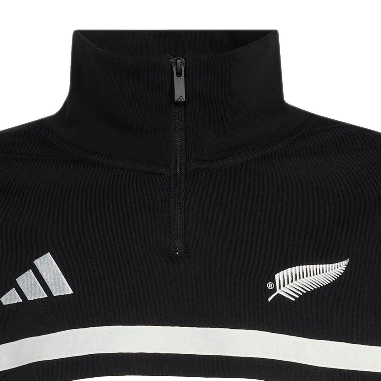Close-up of the adidas All Blacks 26/27 Leisurewear 1/4 Zip Sweatshirt, a black pullover featuring a white fern emblem on the right and a white geometric logo on the left, with two white horizontal stripes below—an iconic piece of New Zealand Rugby leisurewear.