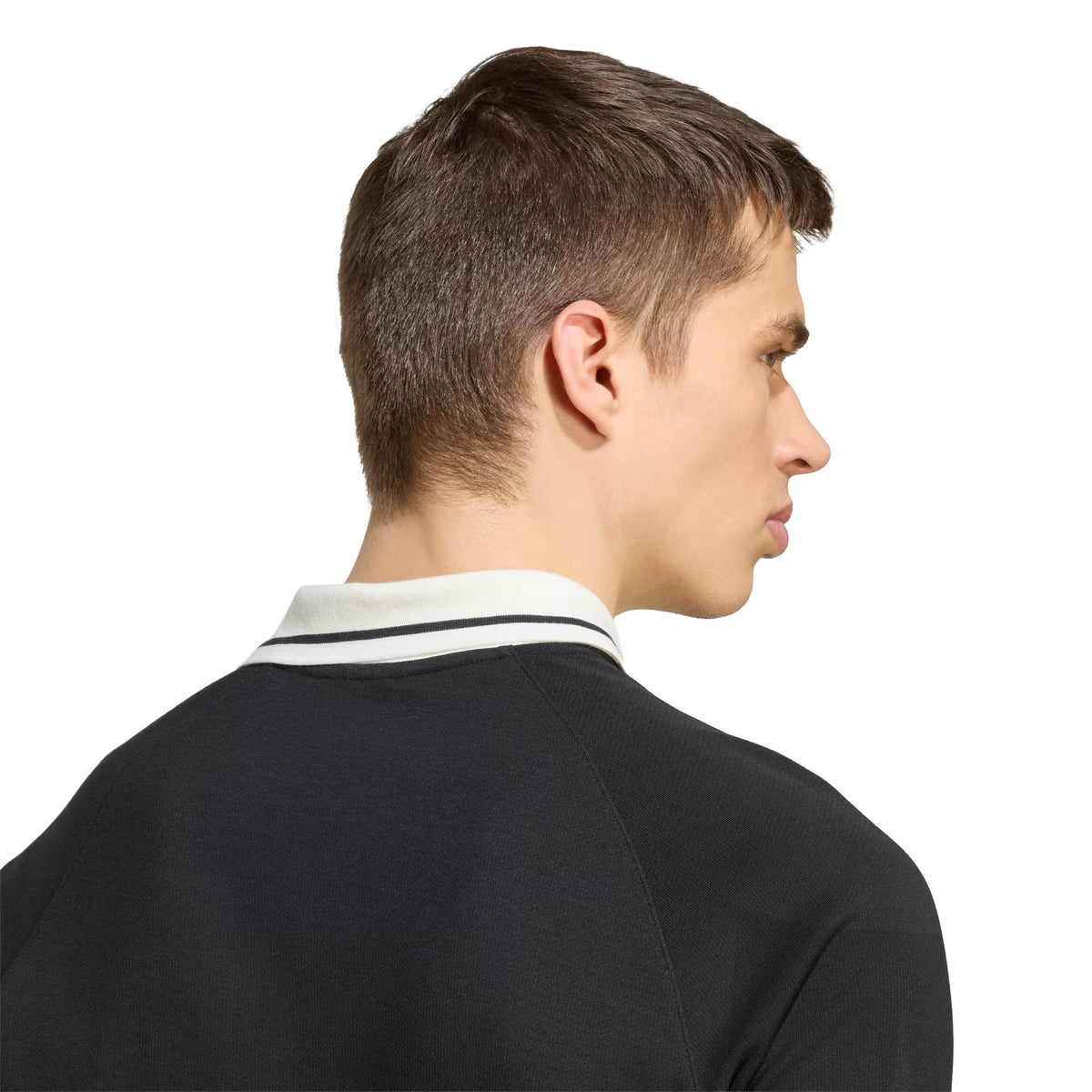 A person with short brown hair, shown from behind and looking to the right against a white background, is wearing the All Blacks 26/27 Travel Polo by adidas—a black shirt with a white collar.