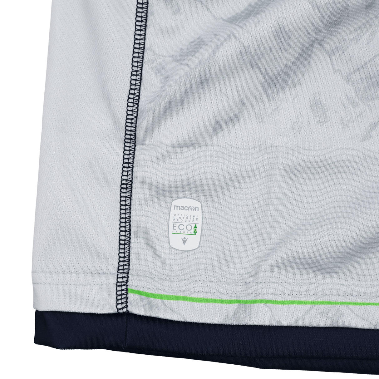 Close-up of the Seattle Seawolves MLR 25/26 Replica Away Jersey by Macron, featuring white fabric with gray patterns, dark blue stitching, a green stripe, and an ECO4 label near the bottom hem—showcasing authentic Macron quality.