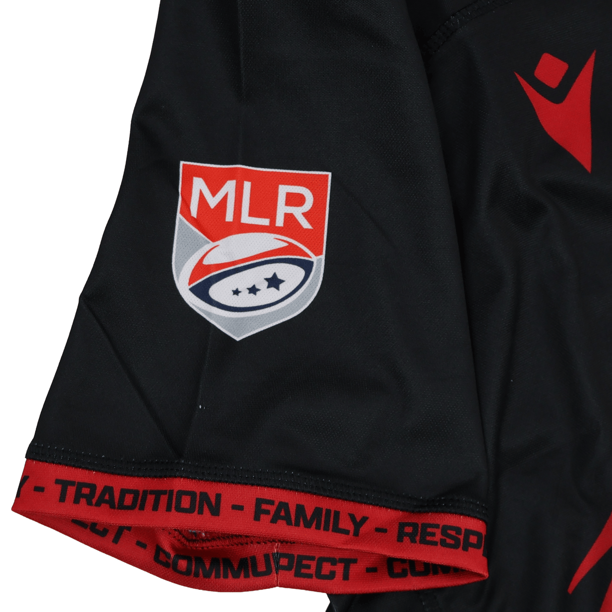 The Utah Warriors MLR 25/26 Replica Home Jersey by Macron features black sleeves with red trim, a Major League Rugby logo patch, and “TRADITION,” “FAMILY,” “RESPECT,” and “COMMUNITY” printed in black.
