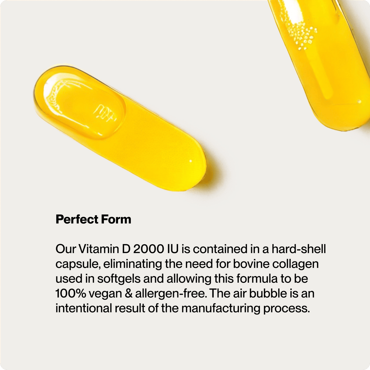 Two yellow Momentous Vitamin D3 2000 IU capsules from Momentous sit on a white surface. The vegan, allergen-free hard-shell capsules support bone health and are air bubble-free for quality.