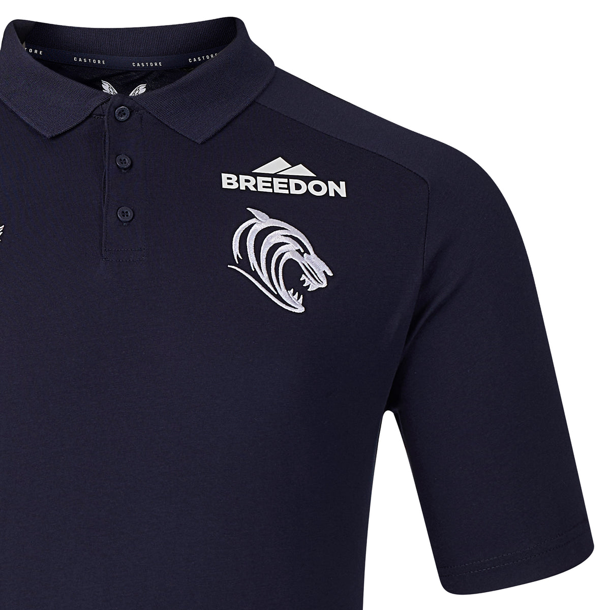 The Leicester 26/27 Off Pitch Polo by Castore is a navy blue shirt featuring a white “Breedon” sponsor logo, a stylized roaring tiger emblem, and three buttons on the front—an elegant polo inspired by the classic Castore rugby shirt.