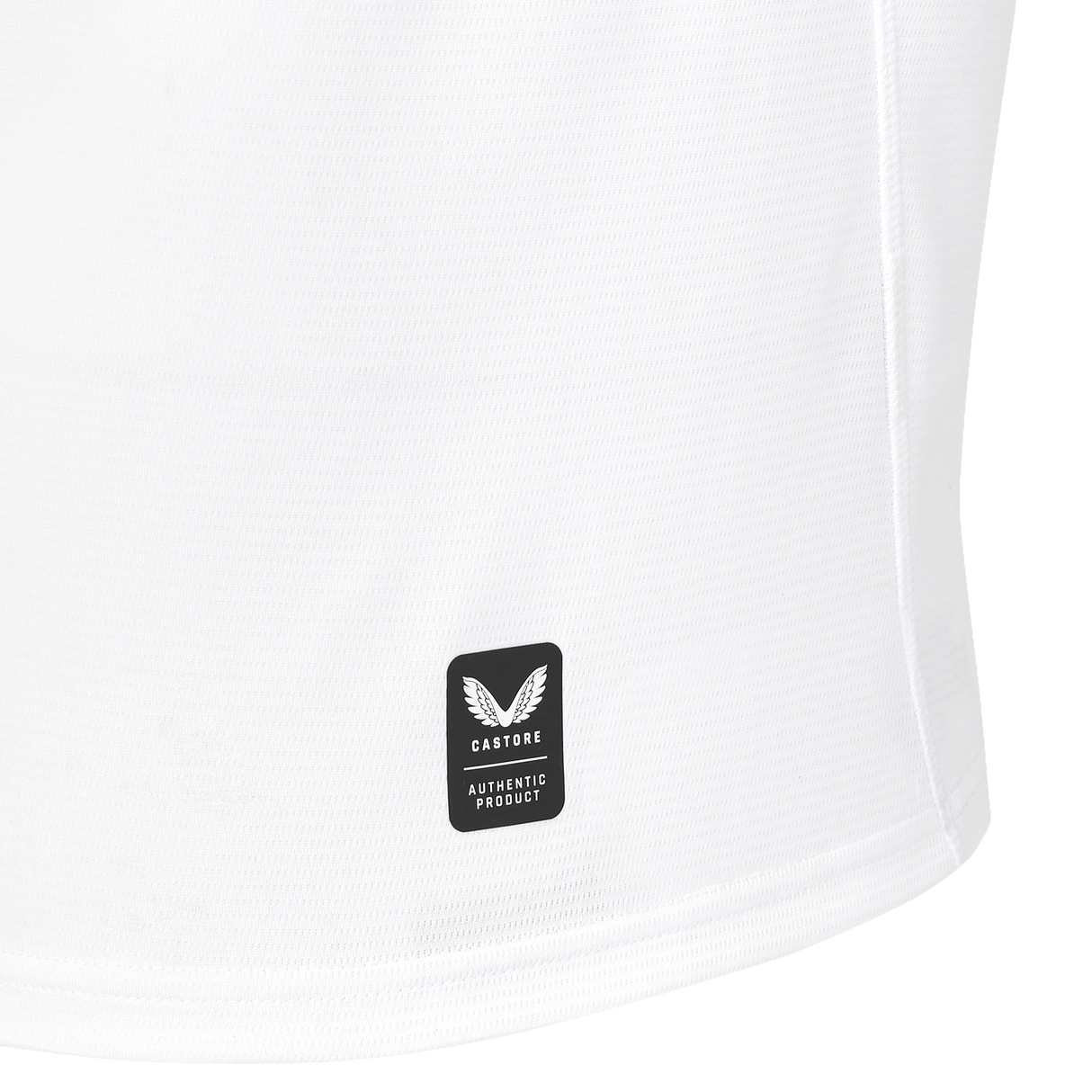 Close-up of the lower portion of a white England 26/27 Replica Home Jersey by Castore, featuring a black rectangular Castore logo tag with “AUTHENTIC PRODUCT” text.