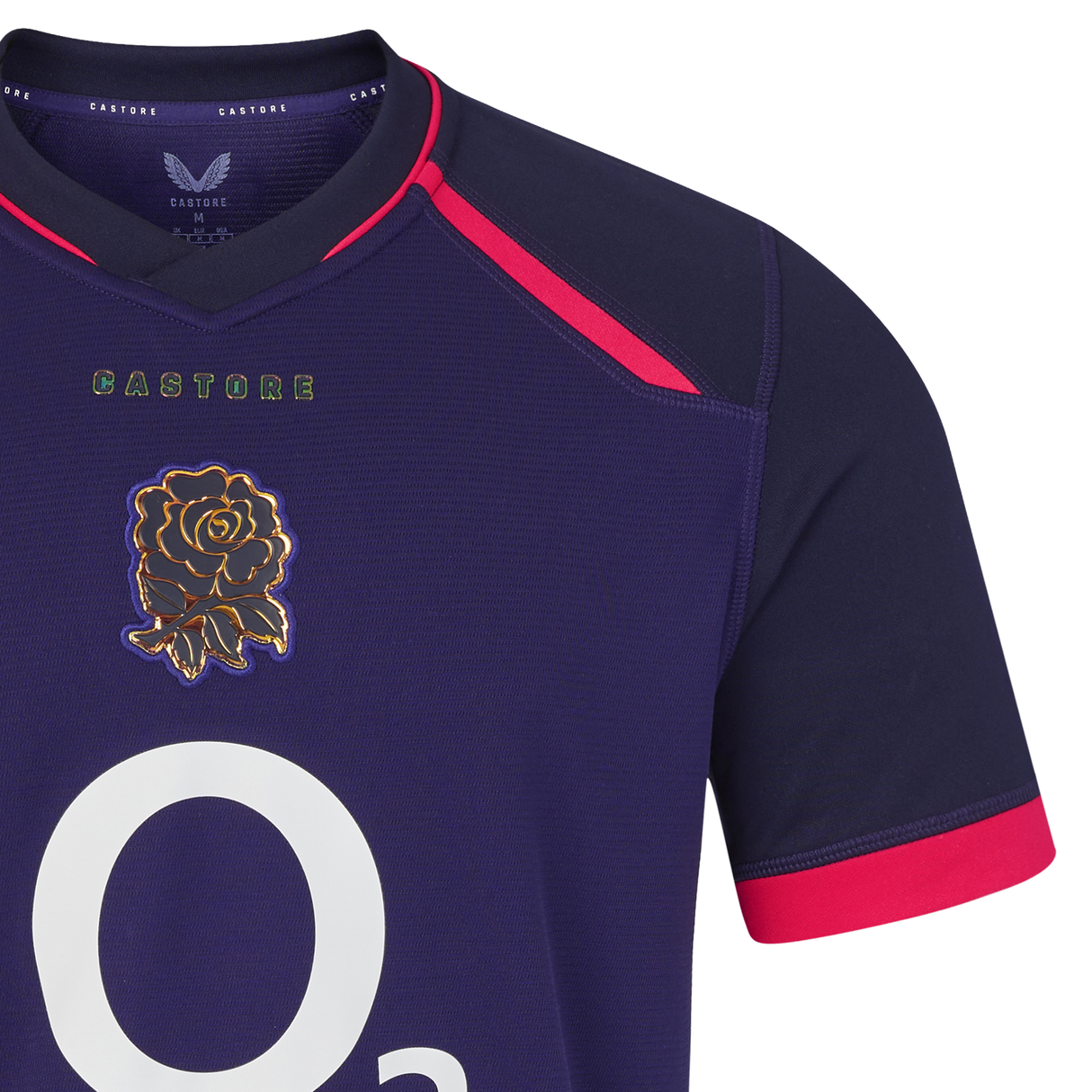 Close-up of the England 26/27 Replica Alternate Jersey by Castore: a navy blue shirt with pink accents, featuring a white “O2” logo and an embroidered gold rose emblem on the chest—a striking replica from Castore’s Rhodonite alternate kit.