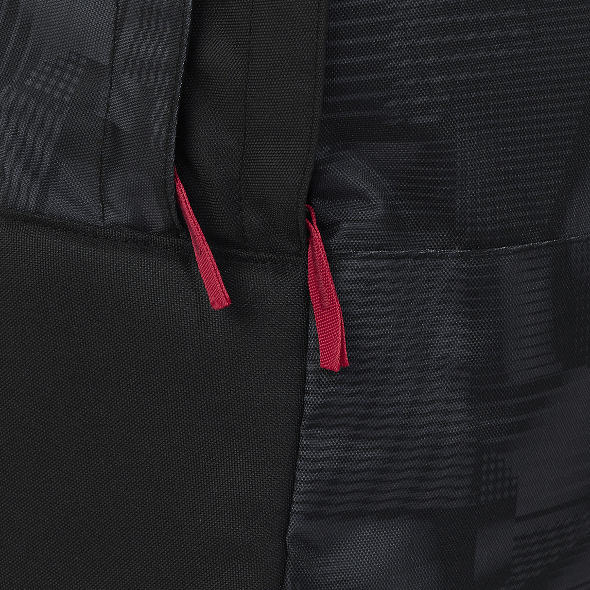 Close-up of the England 26/27 Backpack by Castore, featuring a sleek black design with two red zipper pulls that showcase its stylish and durable construction.