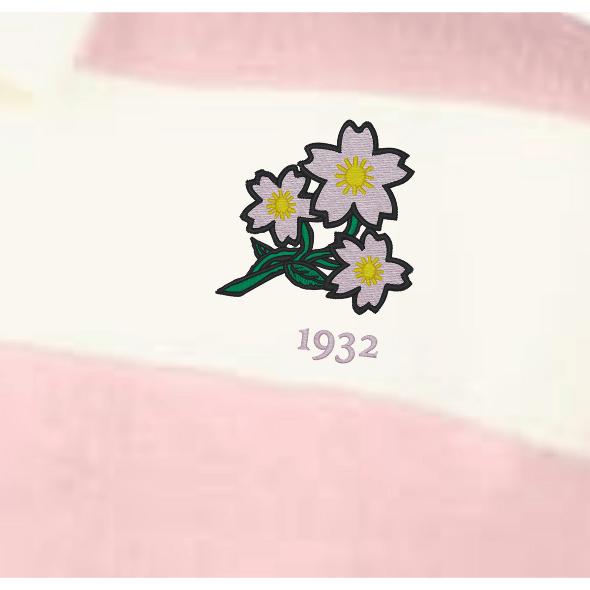 The EMB Augusta Women's Vintage Japan Prep Street Rugby Crop features three pale pink flowers with yellow centers and green stems above "1932," set on pink and white striped fabric for a retro rugby style.