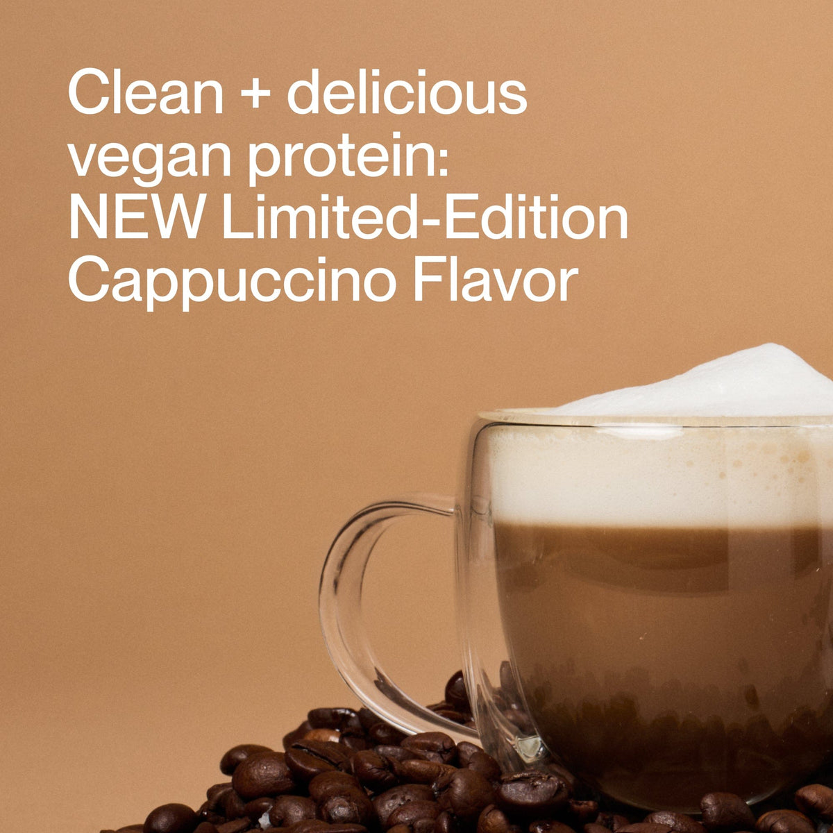A clear glass mug of cappuccino with foam sits among coffee beans on a tan background, promoting Momentous 100% Plant Protein Powder - Limited Edition Flavor, a clean vegan blend for a delicious plant-based boost.