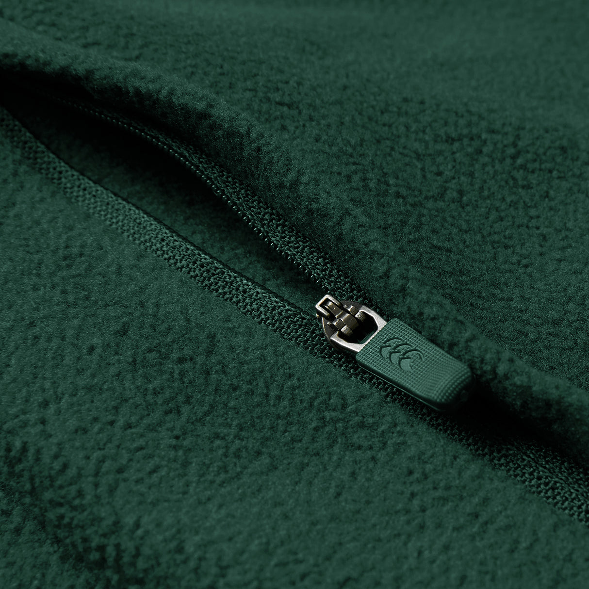 Close-up of the Ireland 26 Retro Fleece 1/4 Zip by Canterbury in green, showing the textured fleece fabric and a partially closed branded zipper pull.