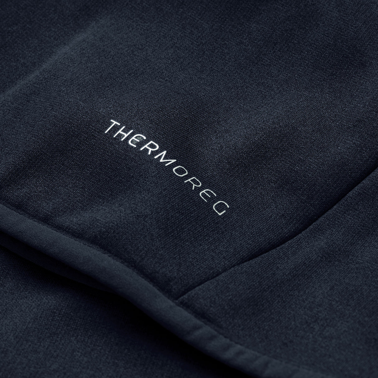Close-up of a dark fabric with the word “THERMOREG” printed in white, highlighting Canterbury’s innovative ThermoReg technology featured in the Ireland 26 Hybrid Padded Jacket, designed for effective temperature regulation.