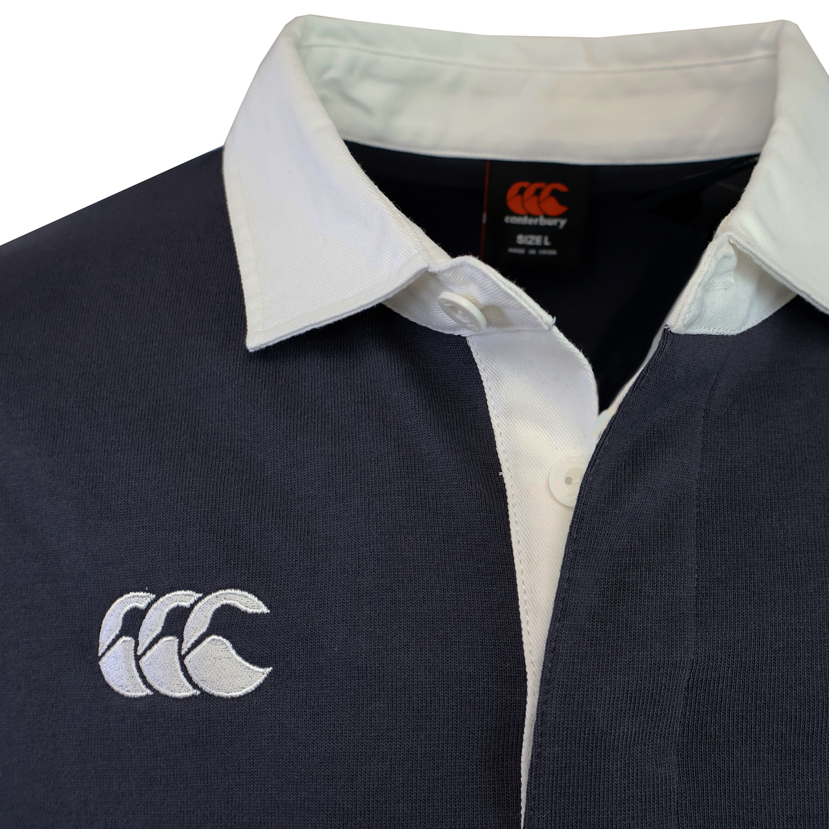 Close-up of the Canterbury Fundamental Solid Dye Long Sleeve Rugby Jersey in navy blue, featuring a white collar and embroidered Canterbury logo on the chest for classic style and versatile wear.