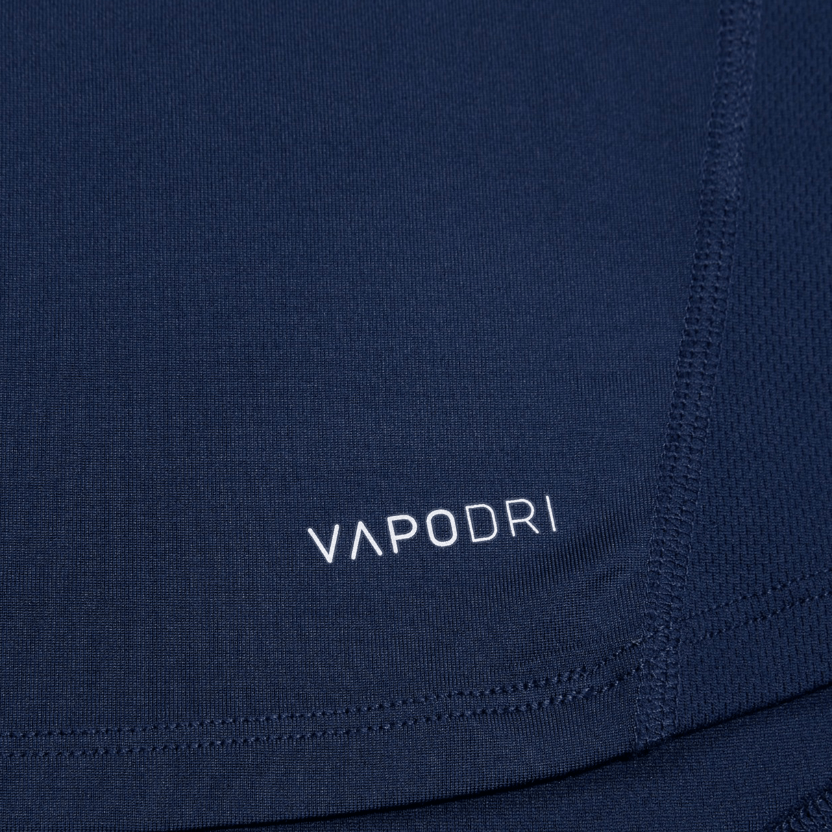 Close-up of the Canterbury Large Logo Superlight Tee fabric in navy, featuring white "VAPODRI" text and seam stitching, showcasing this lightweight performance shirt by Canterbury for rugby training.