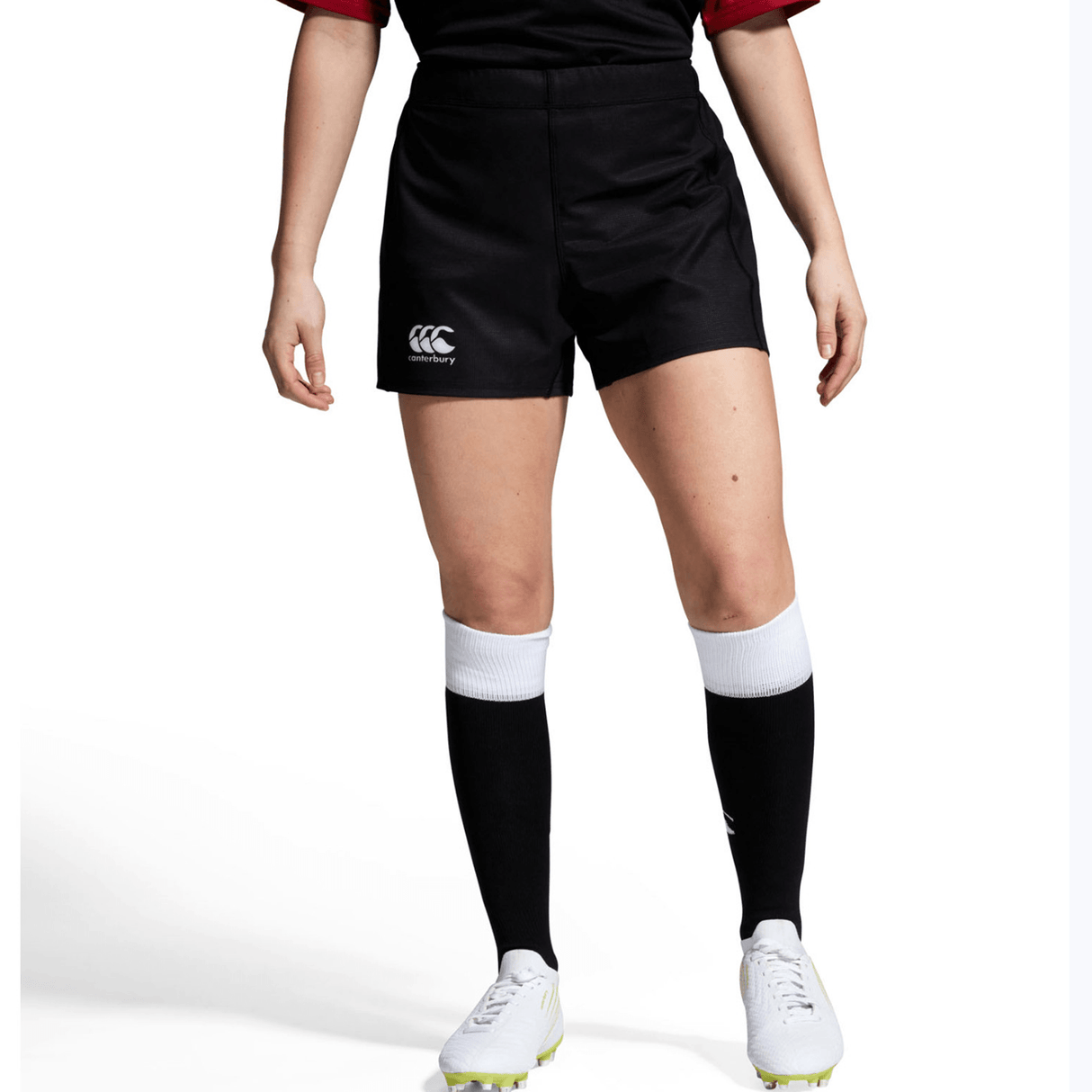 Wearing a sleek black Canterbury sports uniform with Yokohama Shorts, this person completes the look with white and black socks and white cleats, set against a crisp white background.