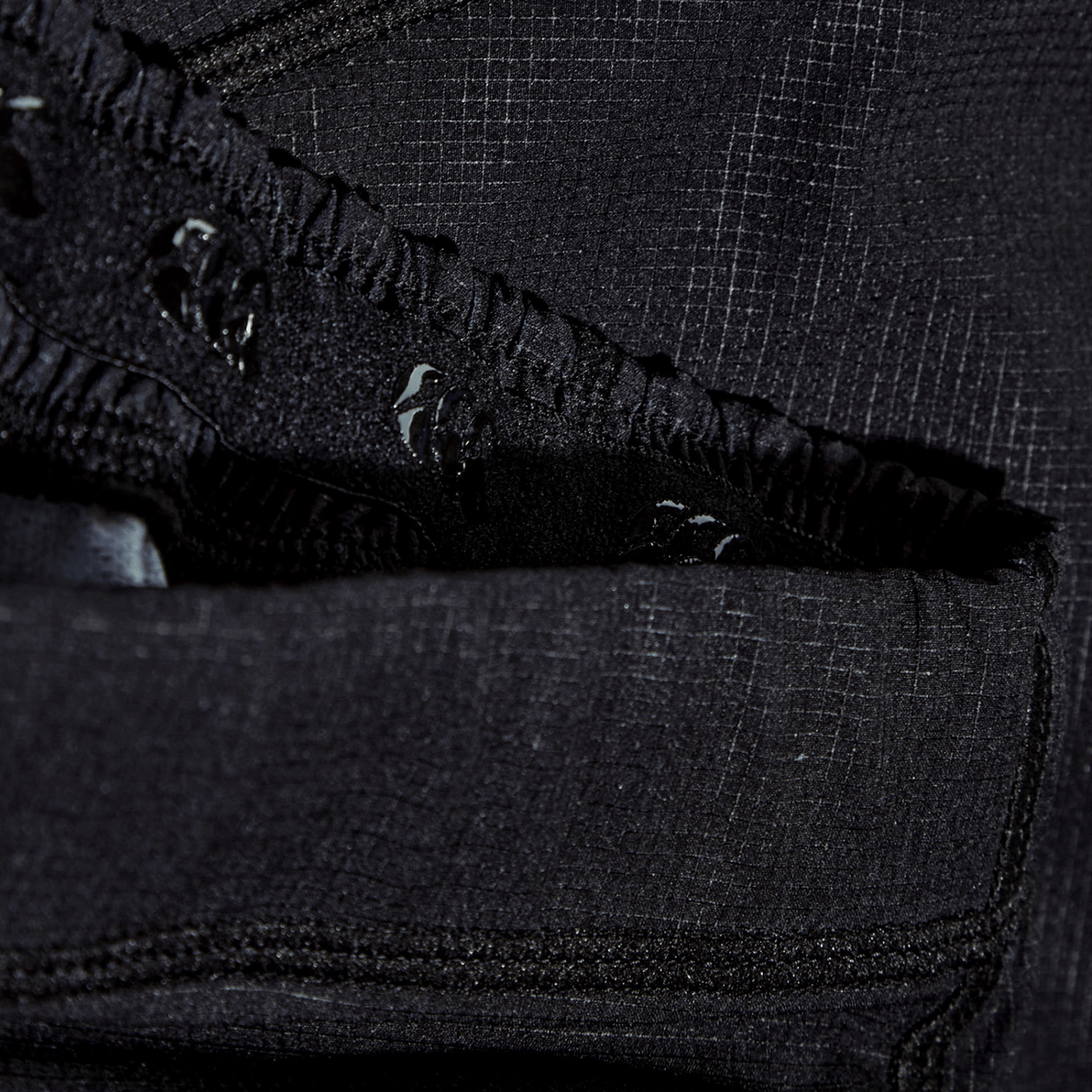 Close-up of the black Yokohama Short's Vapodri fabric by Canterbury, featuring visible seams, textured details, stitched edges, gathered elastic, and a subtle logo.