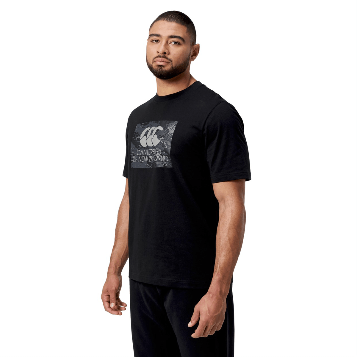 A person stands against a white background, showcasing the Canterbury Force T-Shirt by Canterbury. Its relaxed fit and bold logo give it standout appeal.