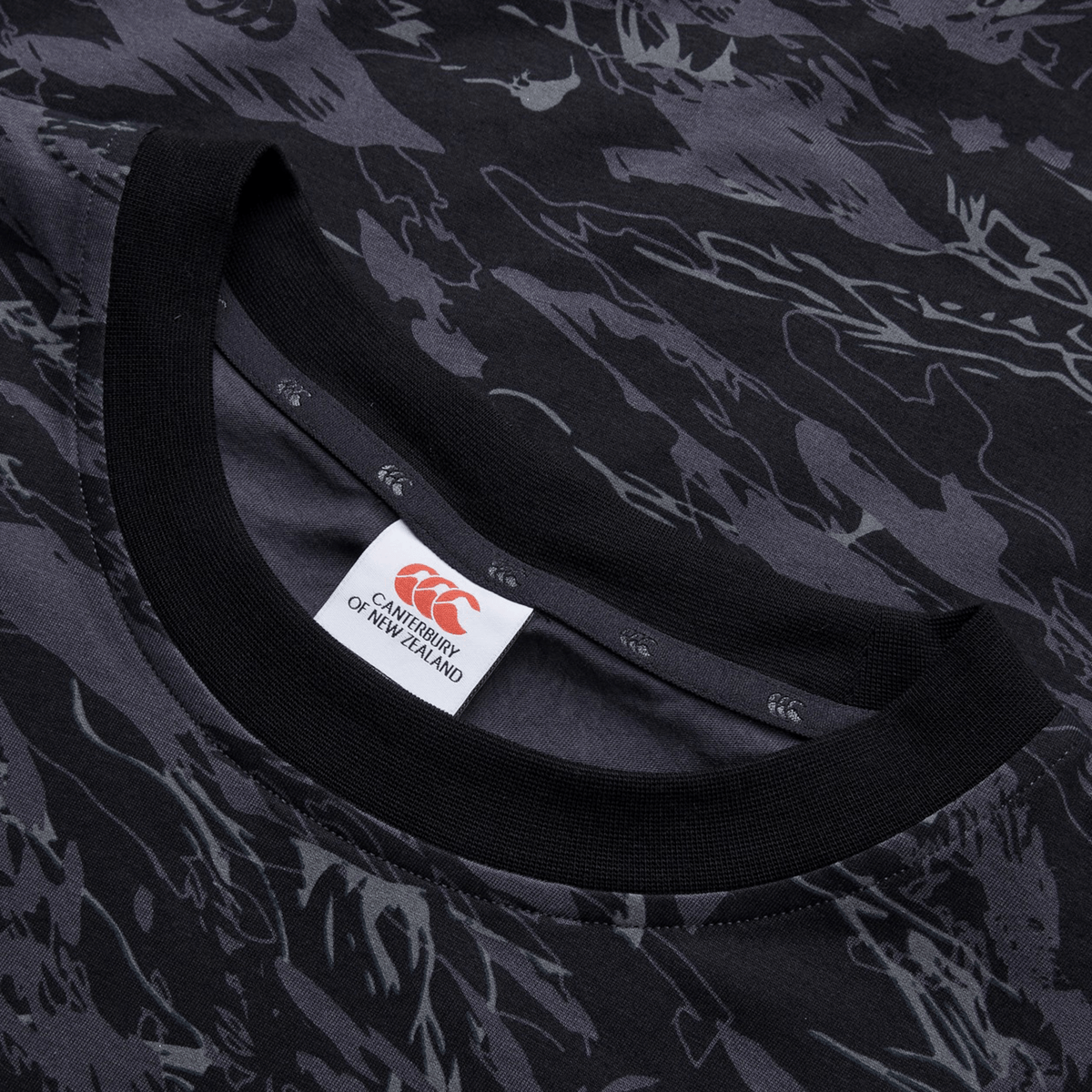 Close-up of the Canterbury Force AOP T-Shirt with a modern crew neck, featuring a black and gray CCC camo print. The authentic touch is added by the Canterbury of New Zealand label at the neckline.