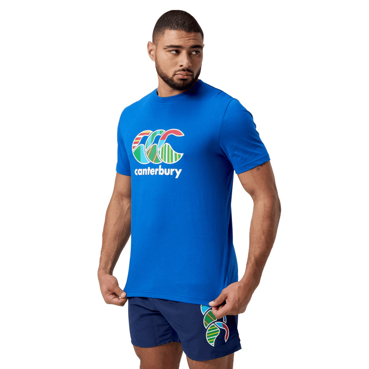 A man in a colorful Canterbury T-shirt and matching shorts gazes to the side.