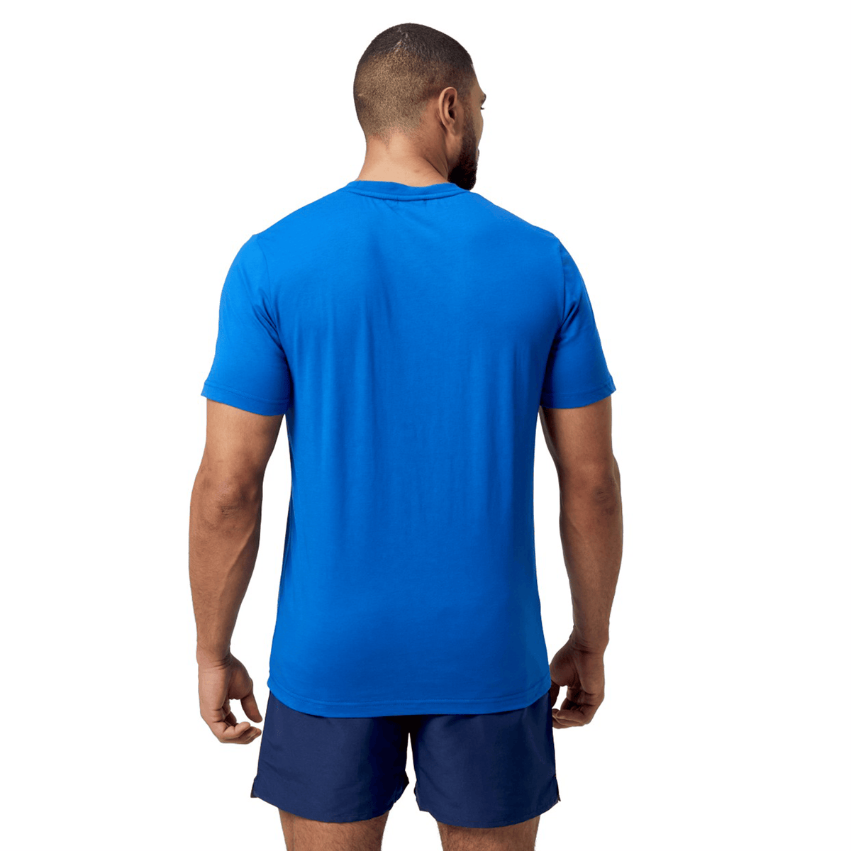 A man stands with his back to the camera, highlighting a vibrant Canterbury Uglies T-Shirt in blue and dark blue shorts.