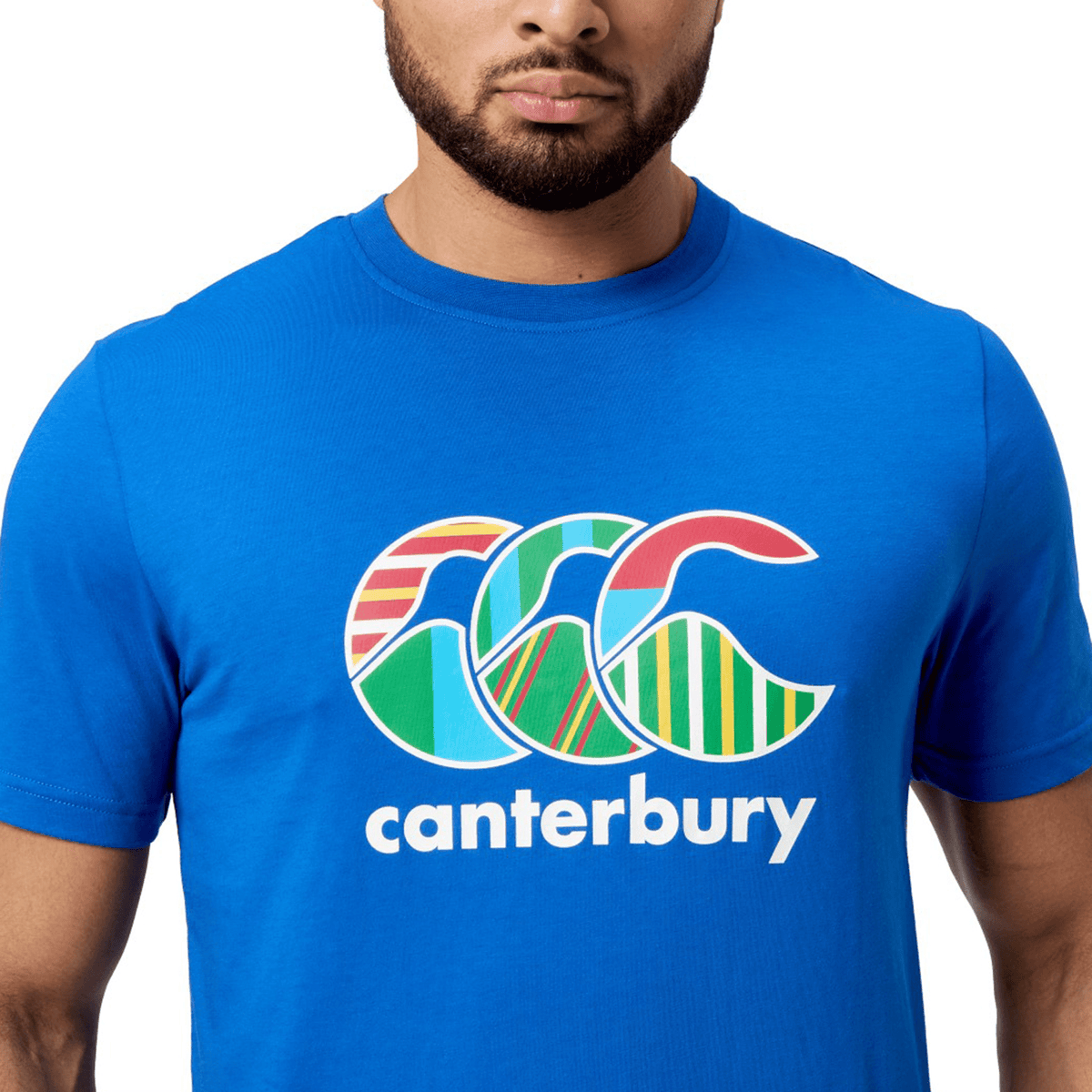 A person wears a Canterbury Uglies T-Shirt in premium cotton, vibrant blue, showcasing a colorful "CCC" logo with "Canterbury" beneath, epitomizing the iconic collection's style.