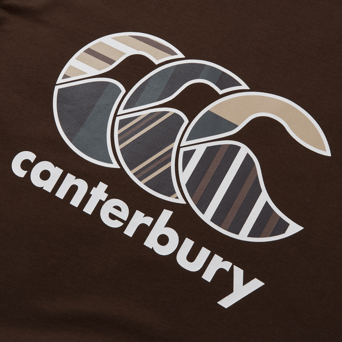 The Canterbury Uglies T-Shirt, by Canterbury, boasts premium cotton in brown with vibrant overlapping striped crescent shapes. The design is completed with the word "Canterbury" elegantly written below.