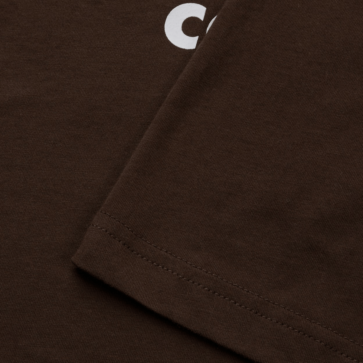The close-up of the Canterbury Uglies T-Shirt from Canterbury shows a vibrant part of a white "C" at the top, with a neatly sewn hem that underscores the premium quality craftsmanship of this cotton t-shirt.